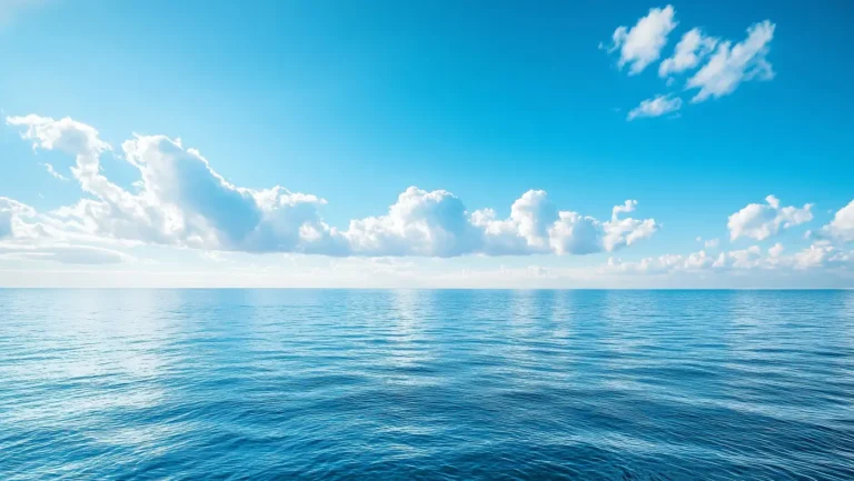 Ein weiter Blick über das ruhige, tiefblaue Meer unter einem klaren, hellblauen Himmel mit sanften, weißen Wolken. Die Wasseroberfläche reflektiert das Sonnenlicht in leichten Wellenbewegungen und vermittelt ein Gefühl von unendlicher Weite und Ruhe. Der Horizont erstreckt sich in der Ferne und verbindet Himmel und Meer zu einer harmonischen Szenerie voller Gelassenheit und Klarheit.