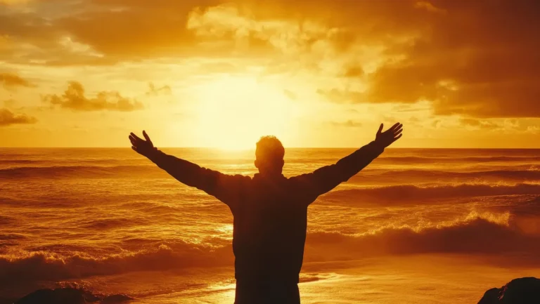 Eine Person steht mit ausgebreiteten Armen am Ufer des Meeres und blickt in einen leuchtenden Sonnenaufgang. Der Himmel und das Wasser sind in warme goldene und orangefarbene Töne getaucht, während sanfte Wellen die Küste berühren. Die Silhouette der Person hebt sich kraftvoll gegen das helle Licht der aufgehenden Sonne ab.