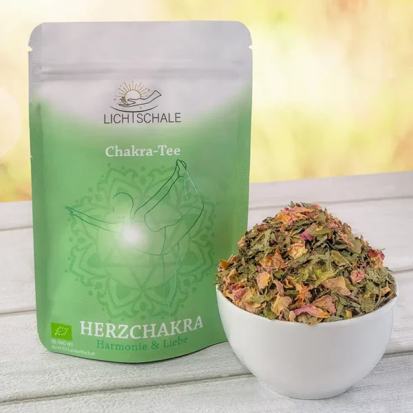 Vorderseite der Verpackung des Herzchakra-Tees von Lich Schale. Grünes Design mit einer stilisierten Figur in einer Yoga-Pose auf einem Mandala-Hintergrund. Aufschrift: ‚Chakra-Tee – Herzchakra – Harmonie & Liebe‘. Daneben eine weiße Schale mit dem losen Kräutertee, erkennbar mit getrockneten grünen Blättern und rosa Rosenblüten. Unten links EU-Bio-Logo und Hinweis auf nicht EU-Landwirtschaft.