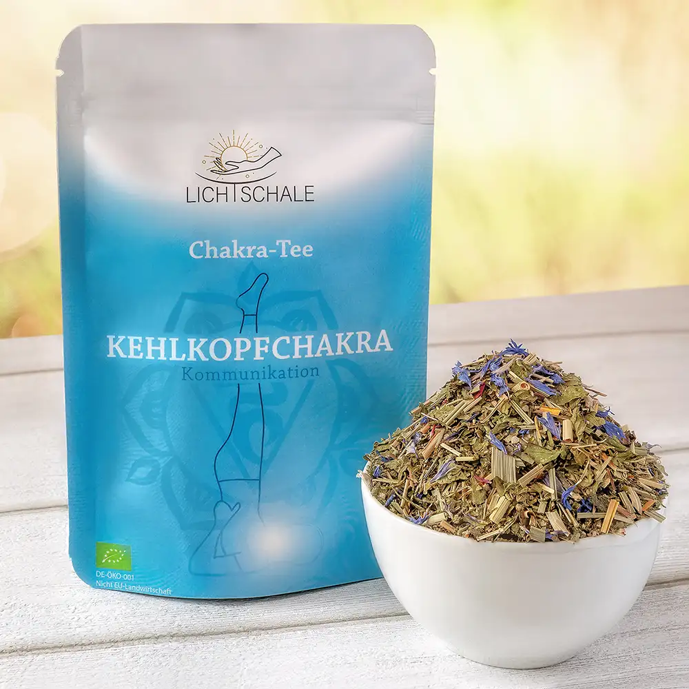Vorderseite der Verpackung des Kehlkopfchakra-Tees von Lich Schale. Hellblaue Verpackung mit der Aufschrift ‚Chakra-Tee Kehlkopfchakra – Kommunikation‘. Im Hintergrund ist ein stilisiertes Chakra-Symbol und eine Yogafigur in Schulterstand-Pose zu sehen. Daneben steht eine weiße Schale mit getrockneten Kräutern, darunter sichtbare blaue Blüten. Unten links das EU-Bio-Siegel.