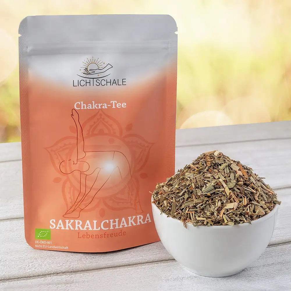 Vorderseite einer orangefarbenen Verpackung für Sakralchakra-Tee der Marke Lich Schale. Auf der Verpackung steht ‘Chakra-Tee – Sakralchakra – Lebensfreude’. Abgebildet ist eine Yoga-Figur in Rückbeuge-Pose mit leuchtendem Punkt im Bauchbereich, darüber ein Mandalasymbol. Daneben eine weiße Schale gefüllt mit grobem Kräutertee
