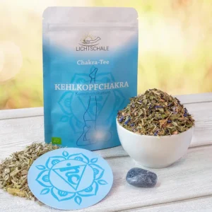 Chakra-Tee-Set für das Kehlkopfchakra mit hellblauer Verpackung, Kräutermischung in weißer Schale, losem Tee, runder Unterlage mit Vishuddha-Symbol und einem blaugrauen Heilstein auf Holzuntergrund